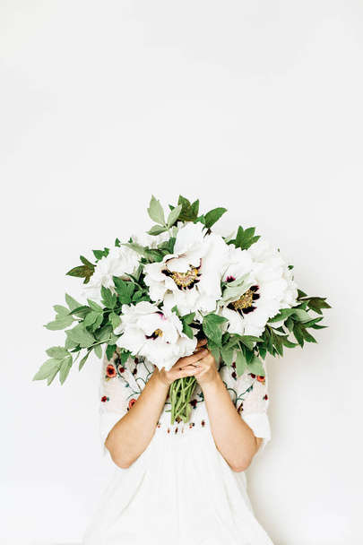 Young pretty woman hold white peony flowers bouquet on white background. Summer floral composition. - Photo, Image