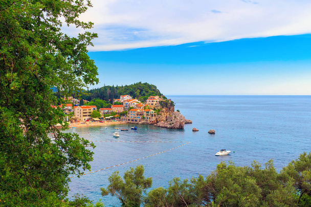 Colorida costa del mar Adriático con casas en la colina rocosa en Montenegro, hermoso paisaje tropical de verano
. - Foto, Imagen