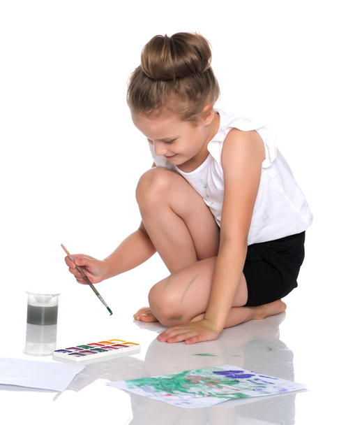 A little girl paints with paint and brush. - Фото, изображение