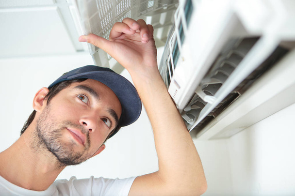 Man looking at air conditioning unit - Фото, изображение