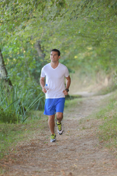 fit male jogger during cross country forest trail - Foto, Imagen