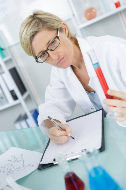 closeup of beautiful lab worker holding up test tube - Zdjęcie, obraz