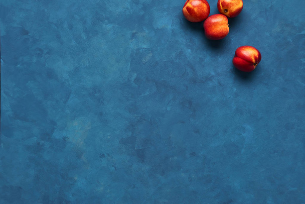 Flat lay of fresh nectarines fruits on blue background. Top view with copy space. - 写真・画像