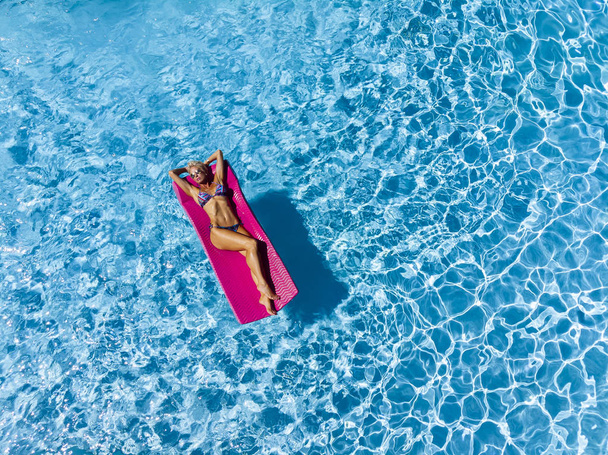 Een mooie rijpe blonde bikini model vormt buiten in de buurt van een zwembad. - Foto, afbeelding