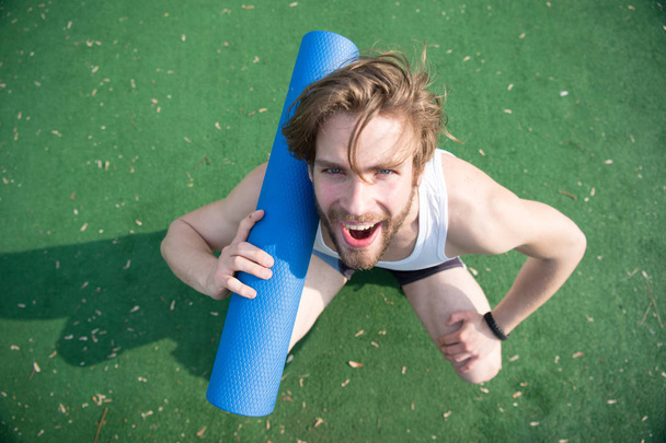 Join yoga. Man athlete cheerful smiling face carries mat, going to stretching. Sportsman carries yoga mat for outdoor practicing. Outdoor yoga concept. Athlete always stretching after workout - Photo, image