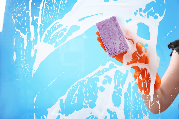 Vidrio de limpieza mujer con esponja contra fondo de color
 - Foto, Imagen