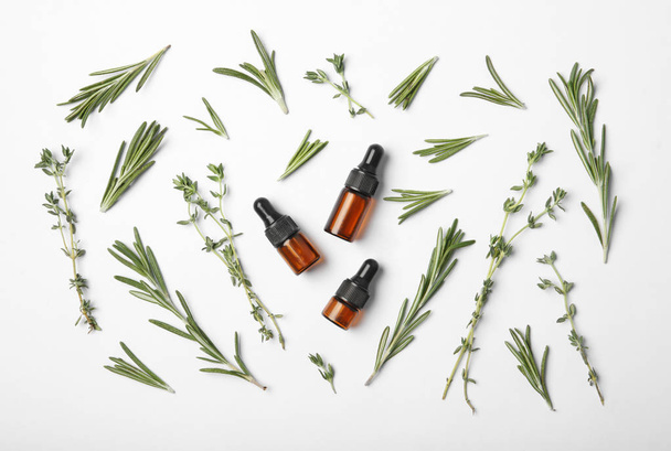 Bottles of rosemary oil and fresh twigs on white background, top view - Photo, image