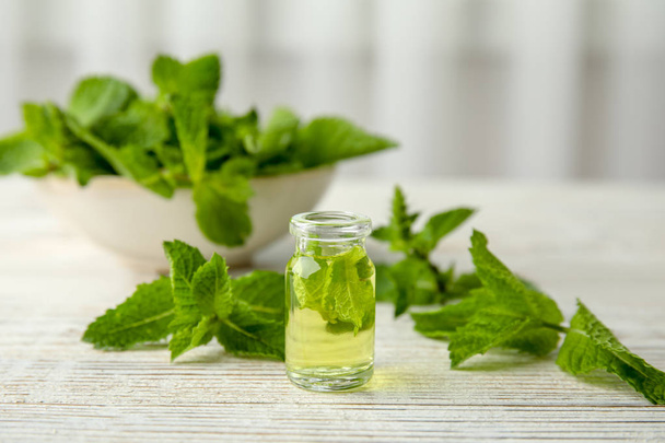 Bottle of essential oil and mint on table - Zdjęcie, obraz