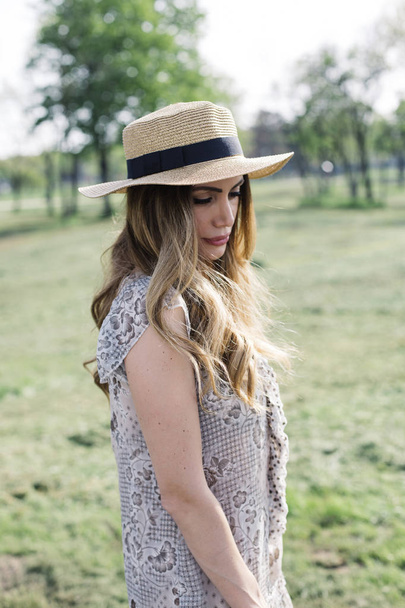 Portret van een mooie elegante vrouw met hoed poseren in het park op zonnige zomerdag - Foto, afbeelding