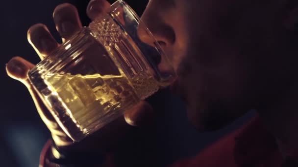 Man in a red shirt is drinking whiskey at the bar - Кадри, відео