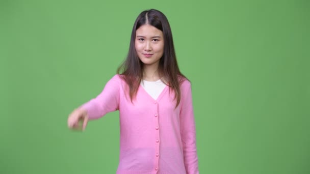 Young beautiful Asian woman pointing at camera - Filmati, video