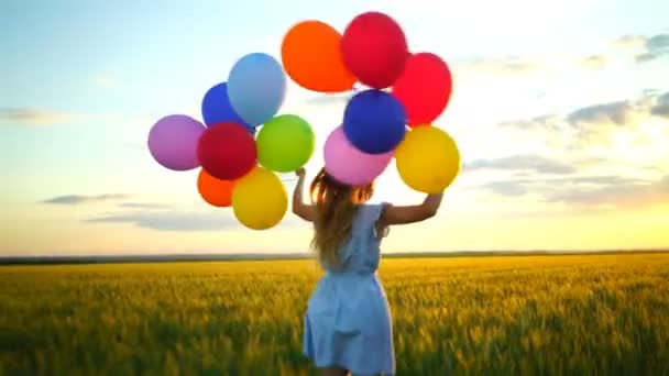 onnellinen nainen, jolla on ilmapalloja juoksemassa vehnäpellolla auringonlaskun aikaan
 - Materiaali, video