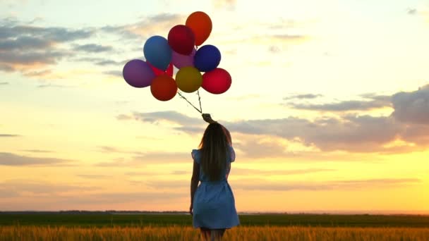 Gelukkige vrouw met ballonnen uitgevoerd in het tarweveld bij zonsondergang - Video