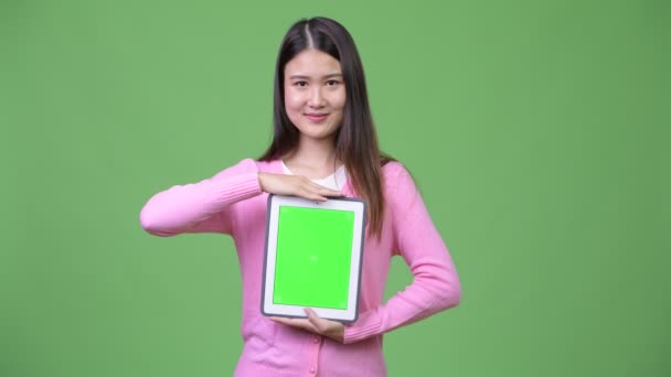 Young beautiful Asian woman showing digital tablet - Materiał filmowy, wideo