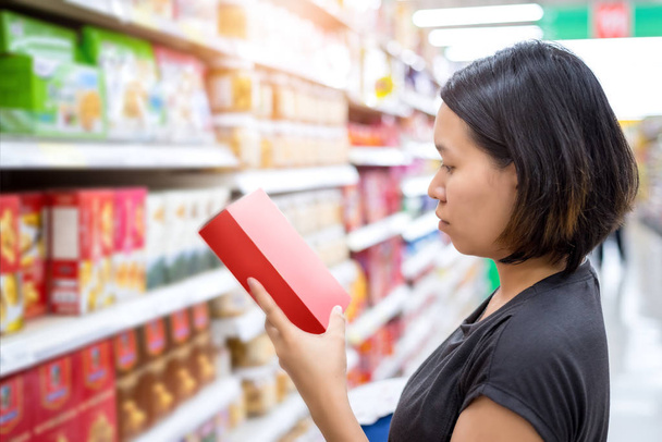 Nuori aasialainen nainen valitsemalla tuotteen ostoksilla meijeri supermarket store
 - Valokuva, kuva