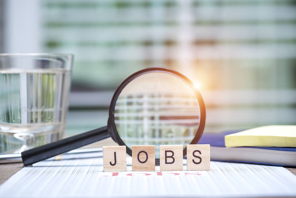 Jobs search concept, Wooden word "Jobs" on white paper and Magnifying glass for jobs search - Fotoğraf, Görsel