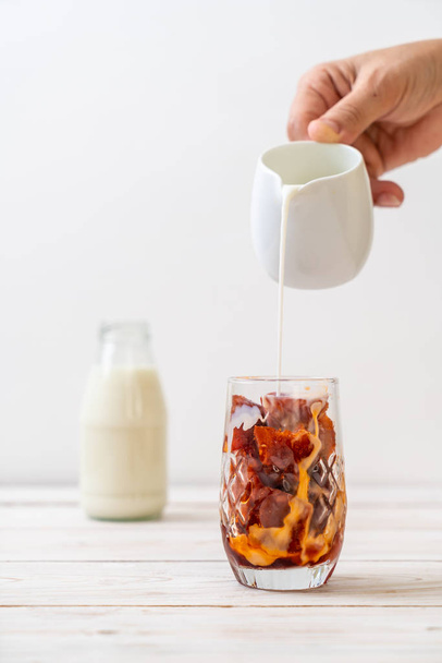 Thai tea ice cube with milk on wood background - Fotó, kép