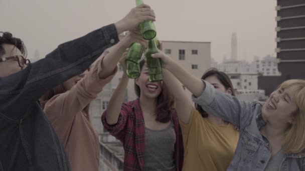 Zeitlupe - eine Gruppe junger asiatischer Frauen und Männer, die tanzen und die Arme in die Luft strecken, gespielt von einem DJ bei Sonnenuntergang auf dem Dach einer städtischen Party. junge asiatische Freunde hängen mit Bier ab. - Filmmaterial, Video
