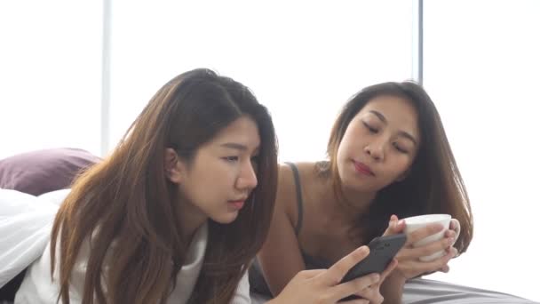 Movimento lento - Jovens mulheres asiáticas bonitas LGBT casal feliz lésbica sentado na cama abraço e usando telefone juntos quarto em casa. Lésbicas casal juntos dentro de conceito. Passar um bom tempo em casa
. - Filmagem, Vídeo