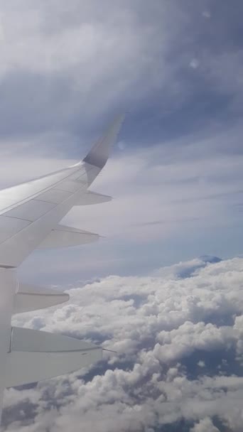 First person view of passenger looking on airplane's wing flying above the clouds - vertical view video - Footage, Video
