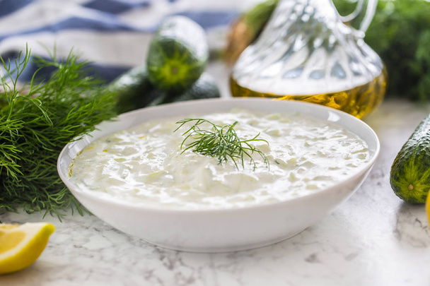 Greek dip sauce or dressing tzatziki prepared  with grated cucumber sour cream yogurt olive oil and fresh dill. - Фото, изображение