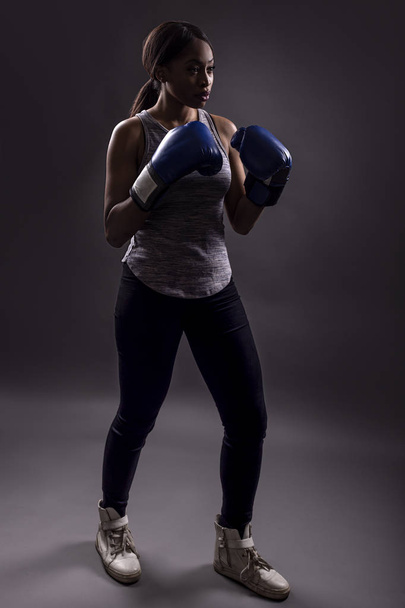 Partial silhouette of an athletic black female wearing boxing gloves training or exercising self defense or MMA. - Φωτογραφία, εικόνα