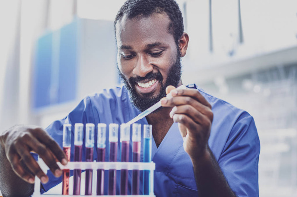 Dark-haired chemist in blue uniform smiling - Fotografie, Obrázek