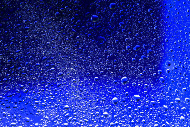Wassertropfen auf blauer Oberfläche. Makro abstraktes Foto, Hintergrund - Foto, Bild