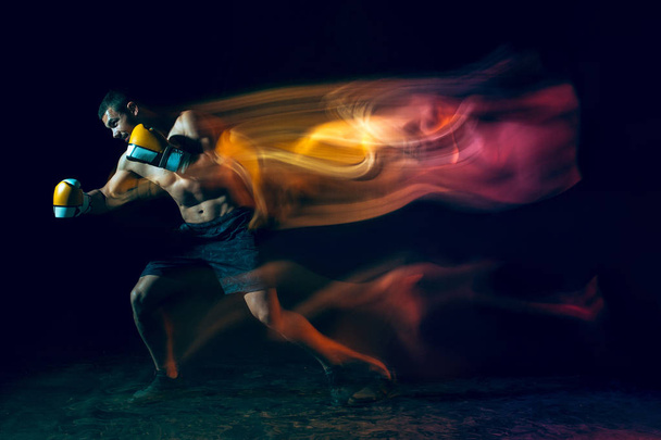 Male boxer boxing in a dark studio - Foto, immagini