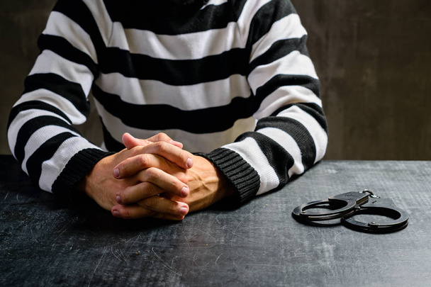 unidentified prisoner in prison stripped uniform sitting in the  - Фото, изображение