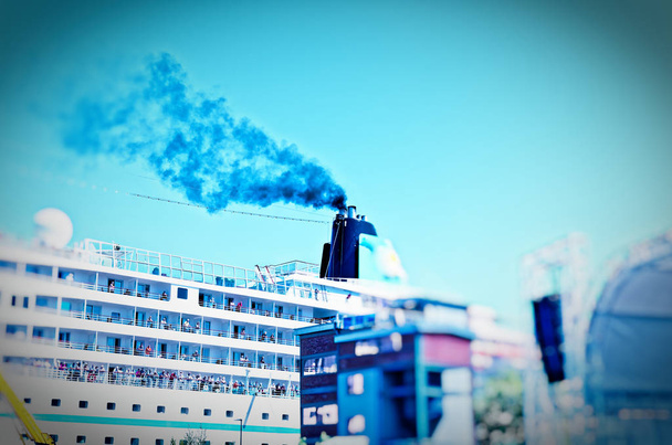 Ship that lies in a harbor with a clear plume of smoke on the chimney to illustrate the air pollution by cruise ships - Photo, Image