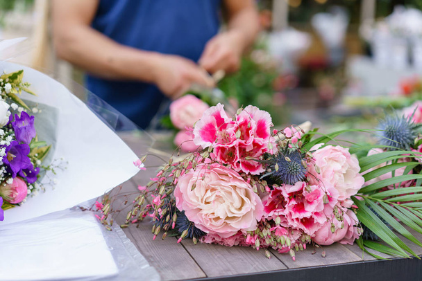 Male florist creating beautiful bouquet in flower shop. outdoor working in flower shop. Man assistant or owner in floral design studio, making decorations and arrangements. - Foto, Bild