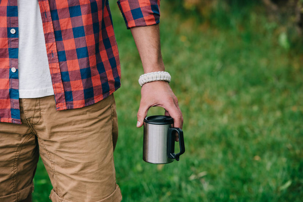 partial view of man in checkered shirt holding mug outdoors  - Photo, Image