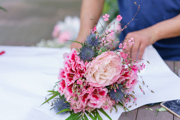 Male florist creating beautiful bouquet in flower shop. outdoor working in flower shop. Man assistant or owner in floral design studio, making decorations and arrangements. - Valokuva, kuva