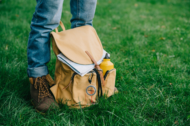 cropped shot of man standing on green grass with backpack - Photo, Image