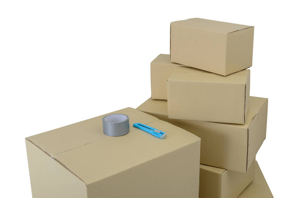 Cajas de cartón en cajas apiladas de diferentes tamaños, cinta adhesiva y cortador aislados sobre fondo blanco con recorrido de recorte
 - Foto, Imagen