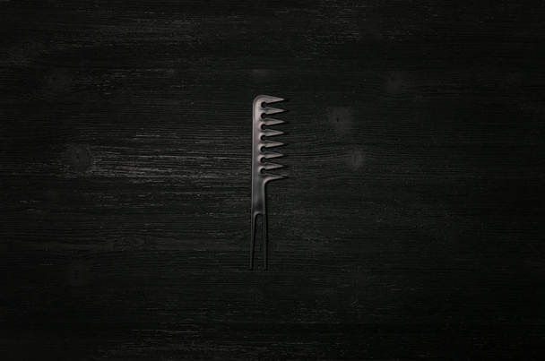 Black plastic hair comb isolated on black wooden background.  - Photo, Image