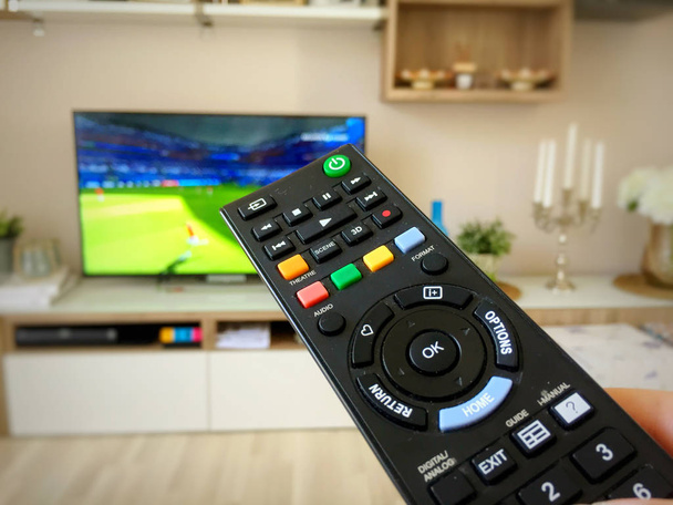Assistir a Copa do Mundo de Futebol na televisão alternando com o controle remoto
 - Foto, Imagem