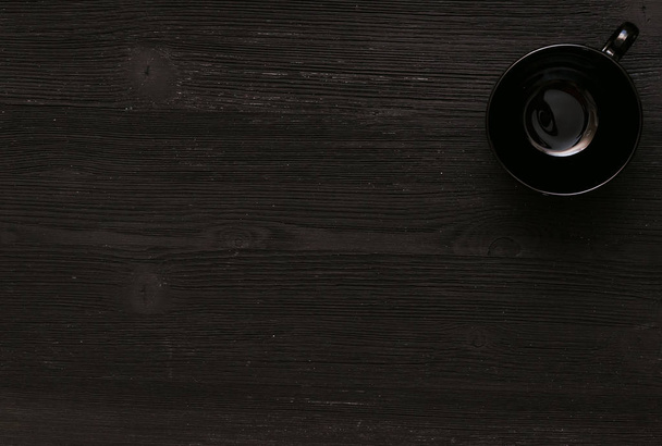 Black empty cup on black wooden kitchen table background with copy space. - Foto, imagen