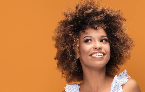 Beauty portrait of smiling african american young woman with afro hairstyle posing on yellow background. - Foto, Imagem