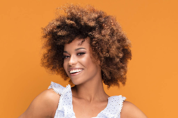 Beauty portrait of smiling african american young woman with afro hairstyle posing on yellow background. - Fotografie, Obrázek