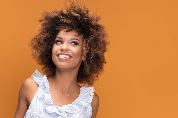 Portret van de schoonheid van lachende Afro-Amerikaanse jonge vrouw met afro kapsel poseren op gele achtergrond. - Foto, afbeelding