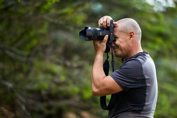 Photographer with professional camera taking pictures in green forest - Φωτογραφία, εικόνα