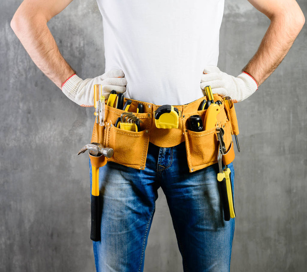 handyman desconhecido com as mãos na cintura e cinto de ferramentas com construção
 - Foto, Imagem