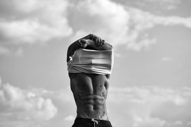 fit mans body. Sexy muscular man undressing on sky background - Photo, image