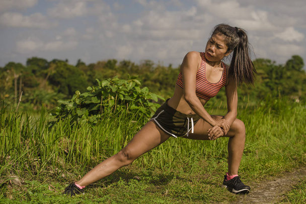 Fit і спортивний бігун азіатські жінки розтяжку ногу і тіло після запуску тренування на зеленому полі красиве тло у спортивні тренування і здоровий спосіб життя концепція - Фото, зображення