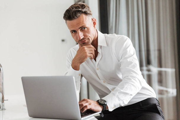Focused man dressed in formal clothes using laptop while sitting at home - Фото, зображення