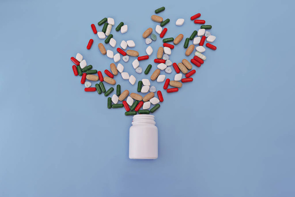 Geneesmiddelen, supplementen en drugs in een fles op blauwe achtergrond - Foto, afbeelding