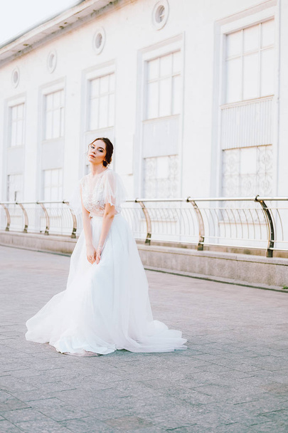 Heureuse jeune mariée en robe blanche fluide s'amusant à l'extérieur
 - Photo, image