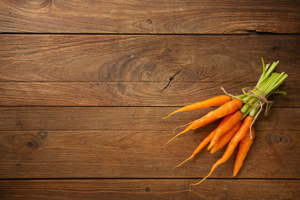 Pile of fresh baby carrots on wooden background - Photo, image